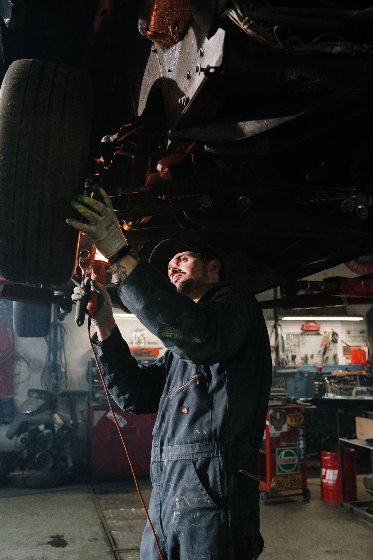 Mechanic using a work light while repairing the underside of a car